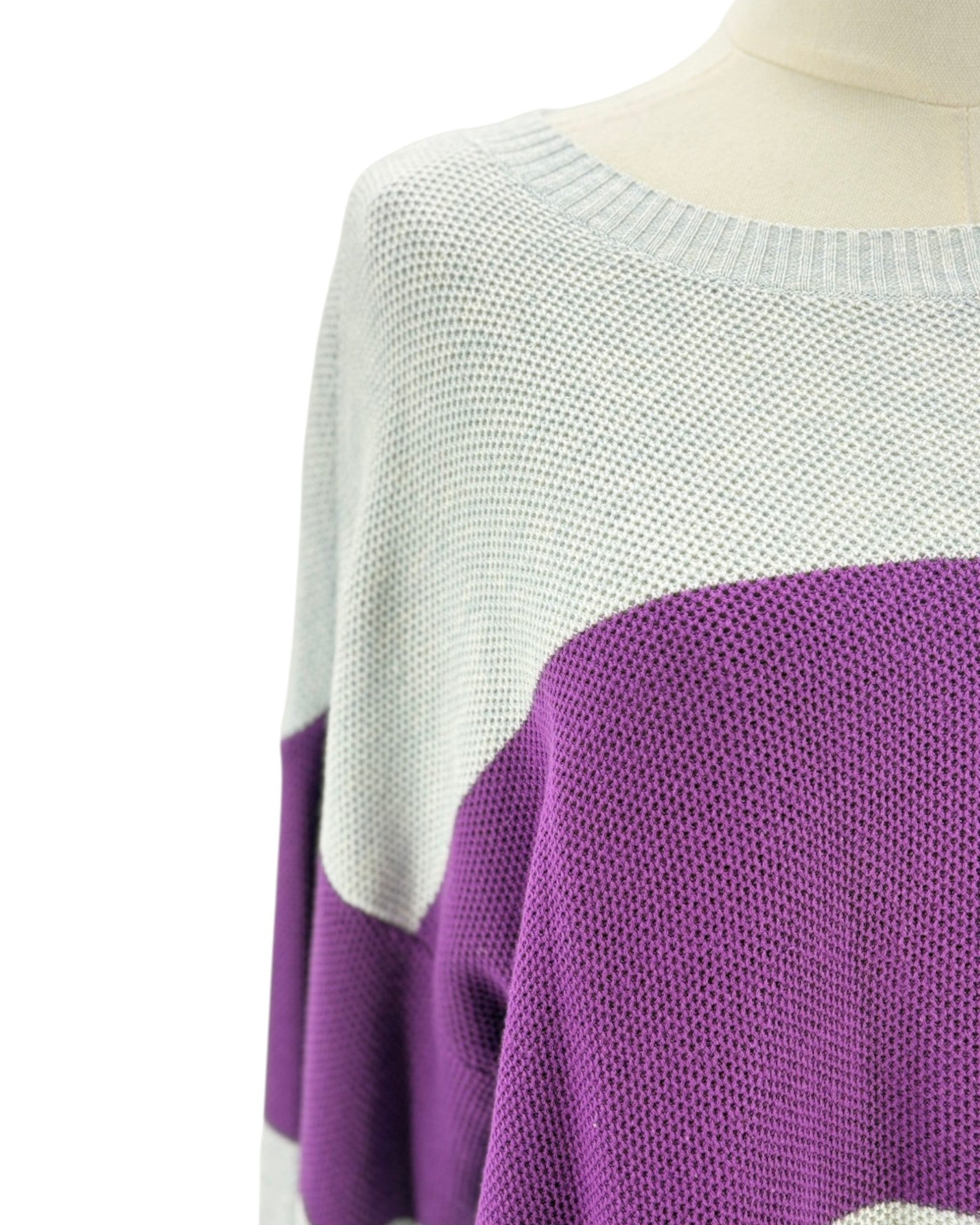 Purple and gray sweater on a mannequin with a plain background