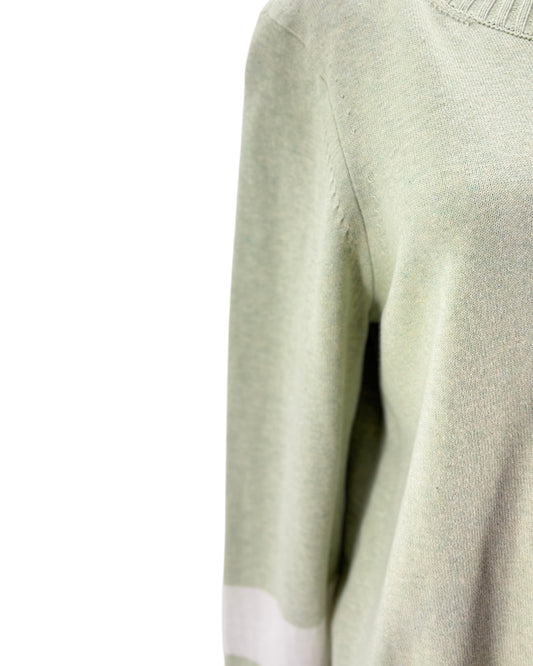 Close-up of a light green sweater with a white patch on a white background