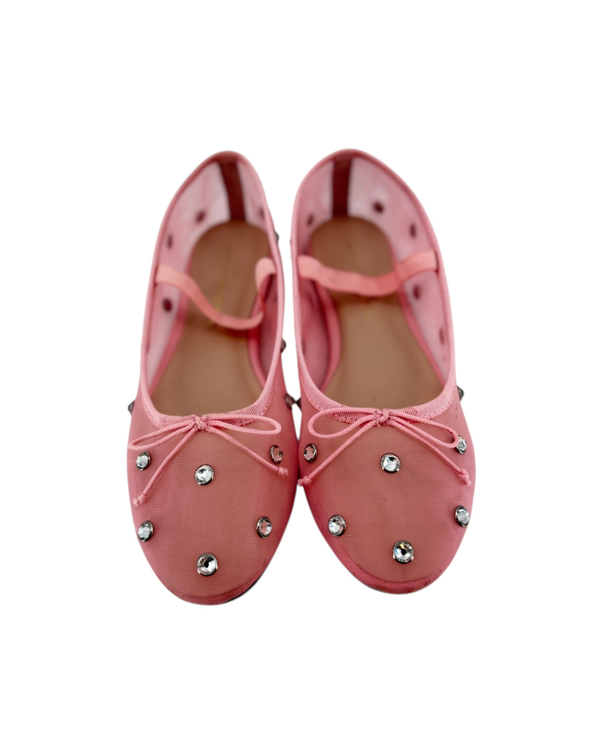 Pink ballet flats with attached jewels and an elastic strap across the top on a white bacground