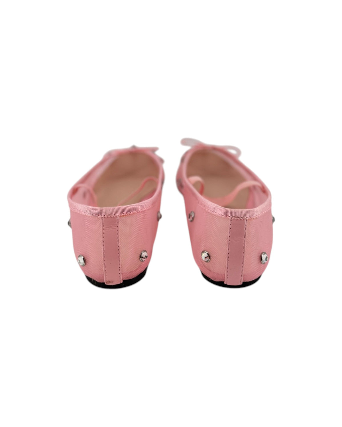 Pink ballet flats with attached jewels and an elastic strap across the top on a white bacground
