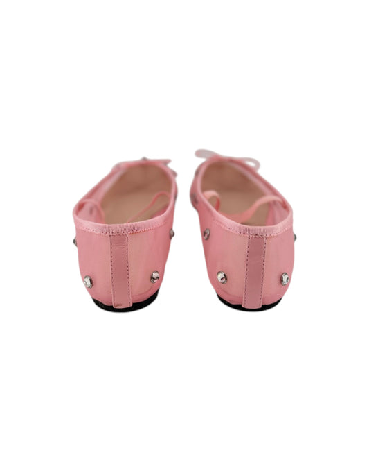 Pink ballet flats with attached jewels and an elastic strap across the top on a white bacground