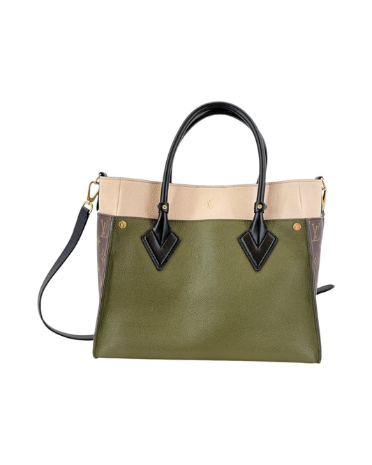 Green handbag with beige top section and black handles on a white background