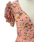 Pink floral dress on a mannequin with ruffled sleeves against a white background