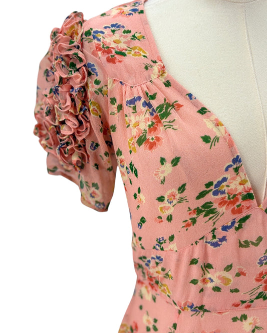 Pink floral dress on a mannequin with ruffled sleeves against a white background