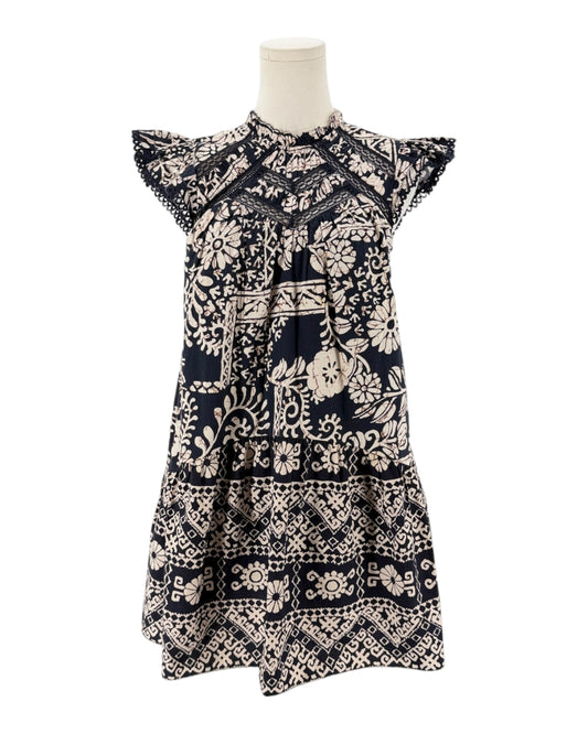 A short-sleeve tiered dress with a navy blue and cream block-print floral pattern, displayed on a mannequin torso against a white background.