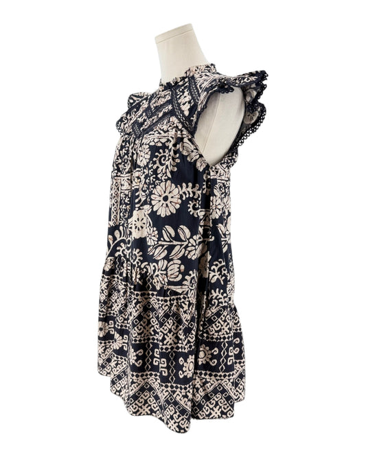 A sleeveless tiered blouse with a navy blue and cream floral/tribal-style print, displayed on a cream mannequin torso against a white background.
