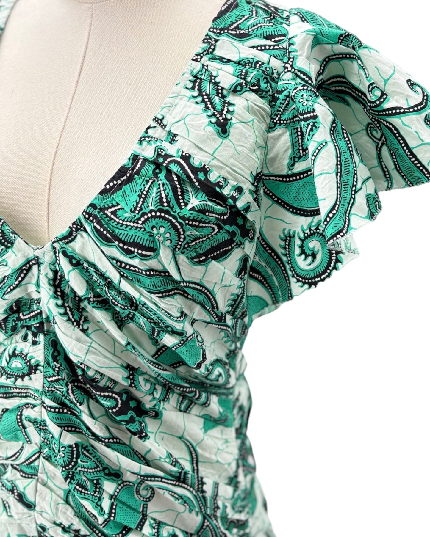 Green and white patterned top on a mannequin with a plain background