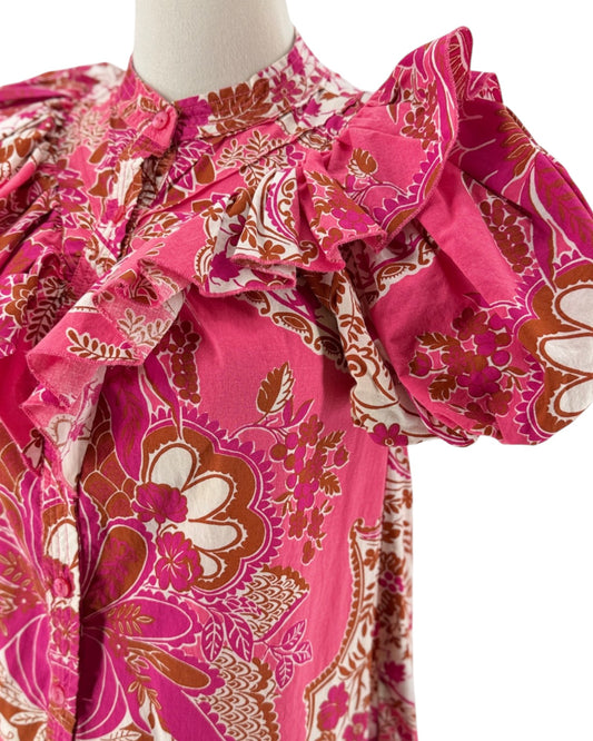 A pink patterned dress displayed on a mannequin torso against a plain white background. The dress features a vibrant pink base with a detailed paisley and floral print in gold, brown, and white, and has dramatic ruffled puff sleeves.
