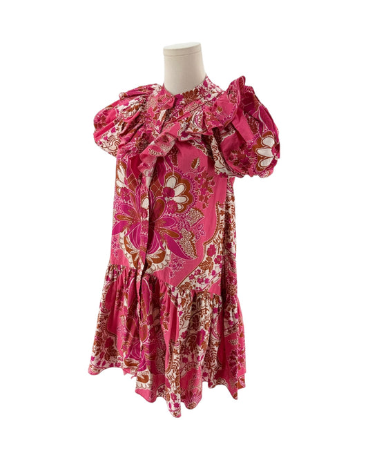 A pink patterned dress displayed on a mannequin torso against a plain white background. The dress features a vibrant pink base with a detailed paisley and floral print in gold, brown, and white, and has dramatic ruffled puff sleeves.