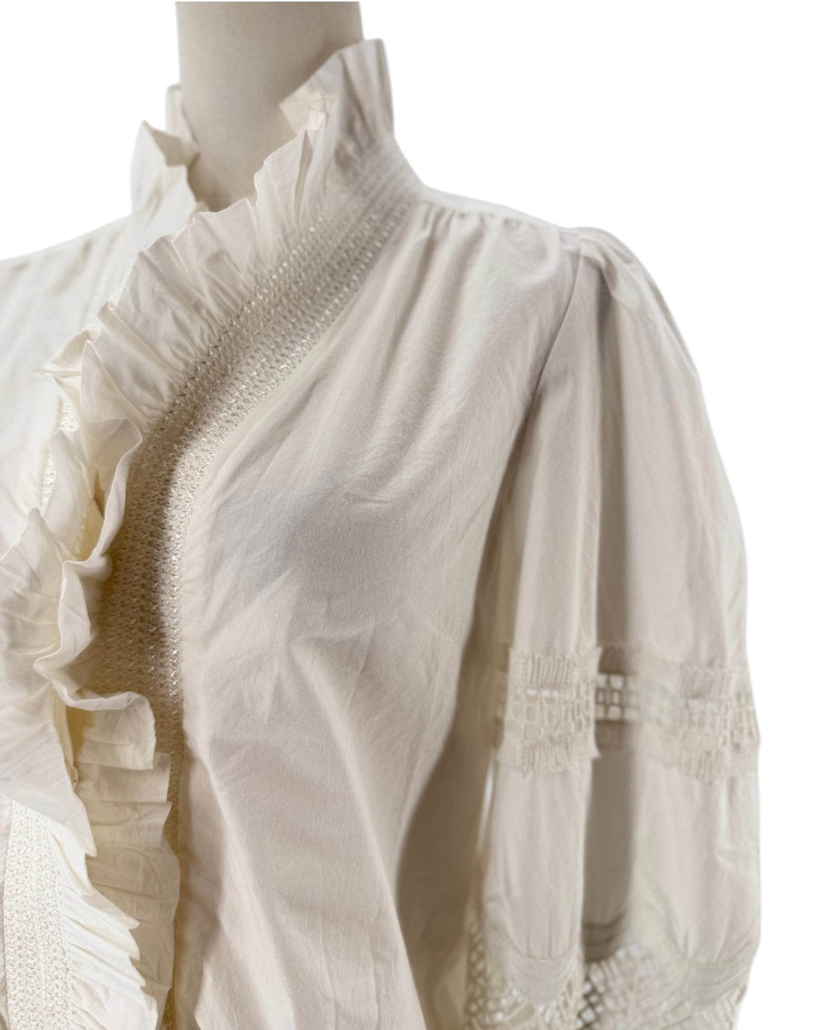 White long sleeve blouse with a ruffle collar and eyelet detailing on the sleeves on a mannequin on a white background