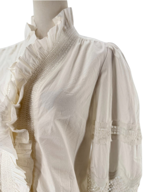White long sleeve blouse with a ruffle collar and eyelet detailing on the sleeves on a mannequin on a white background