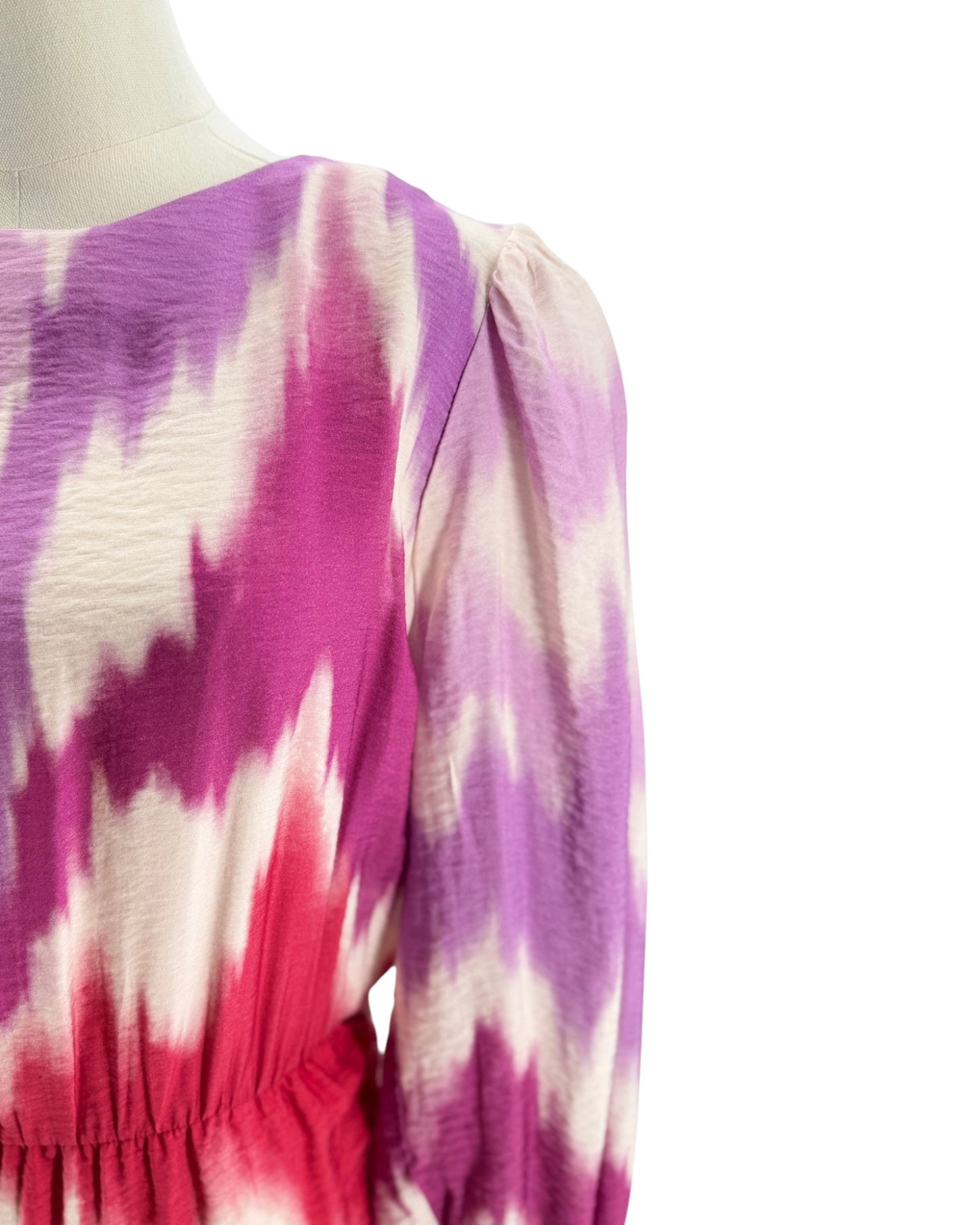 Mannequin wearing a tie-dye dress with pink, purple, and white pattern on a white background