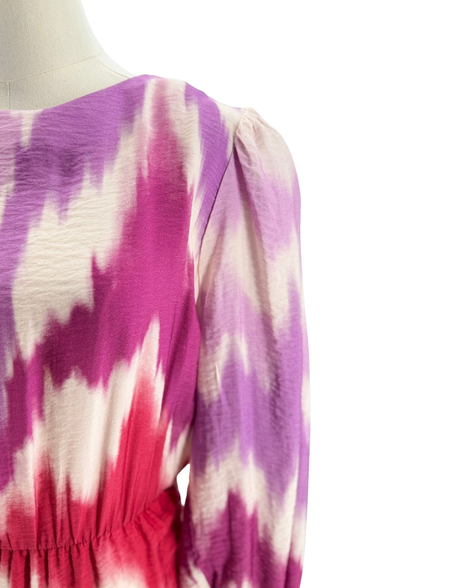 Mannequin wearing a tie-dye dress with pink, purple, and white pattern on a white background