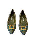 Pair of decorative shoes with gold embellishments on a white background