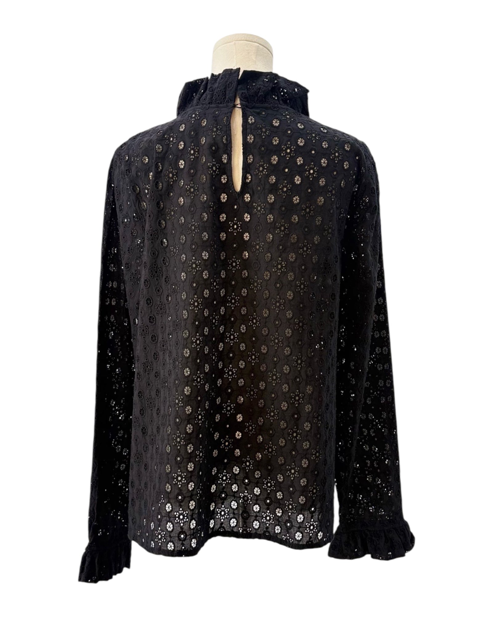 Black blouse with a eyelet pattern on a mannequin against a white background
