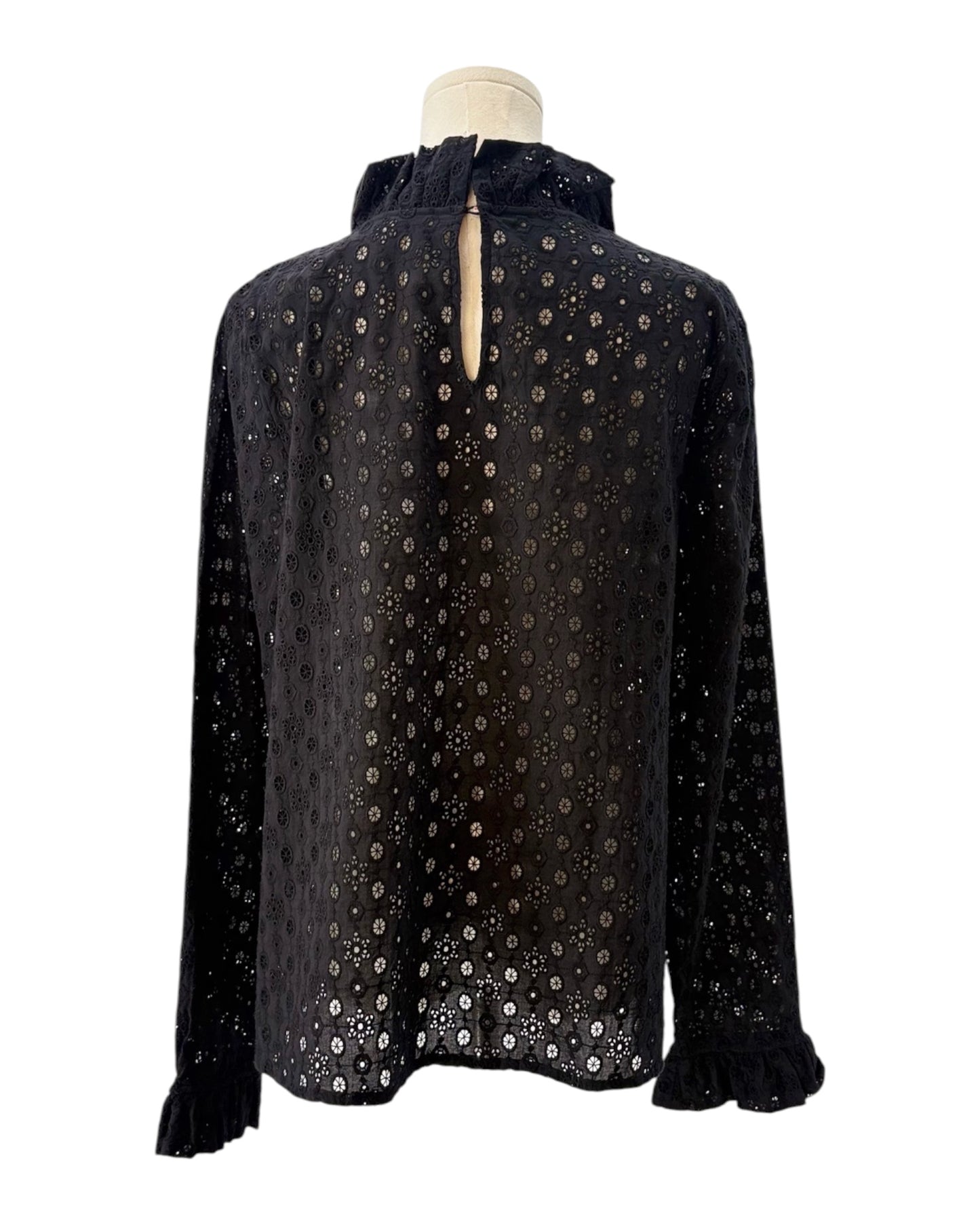 Black blouse with a eyelet pattern on a mannequin against a white background
