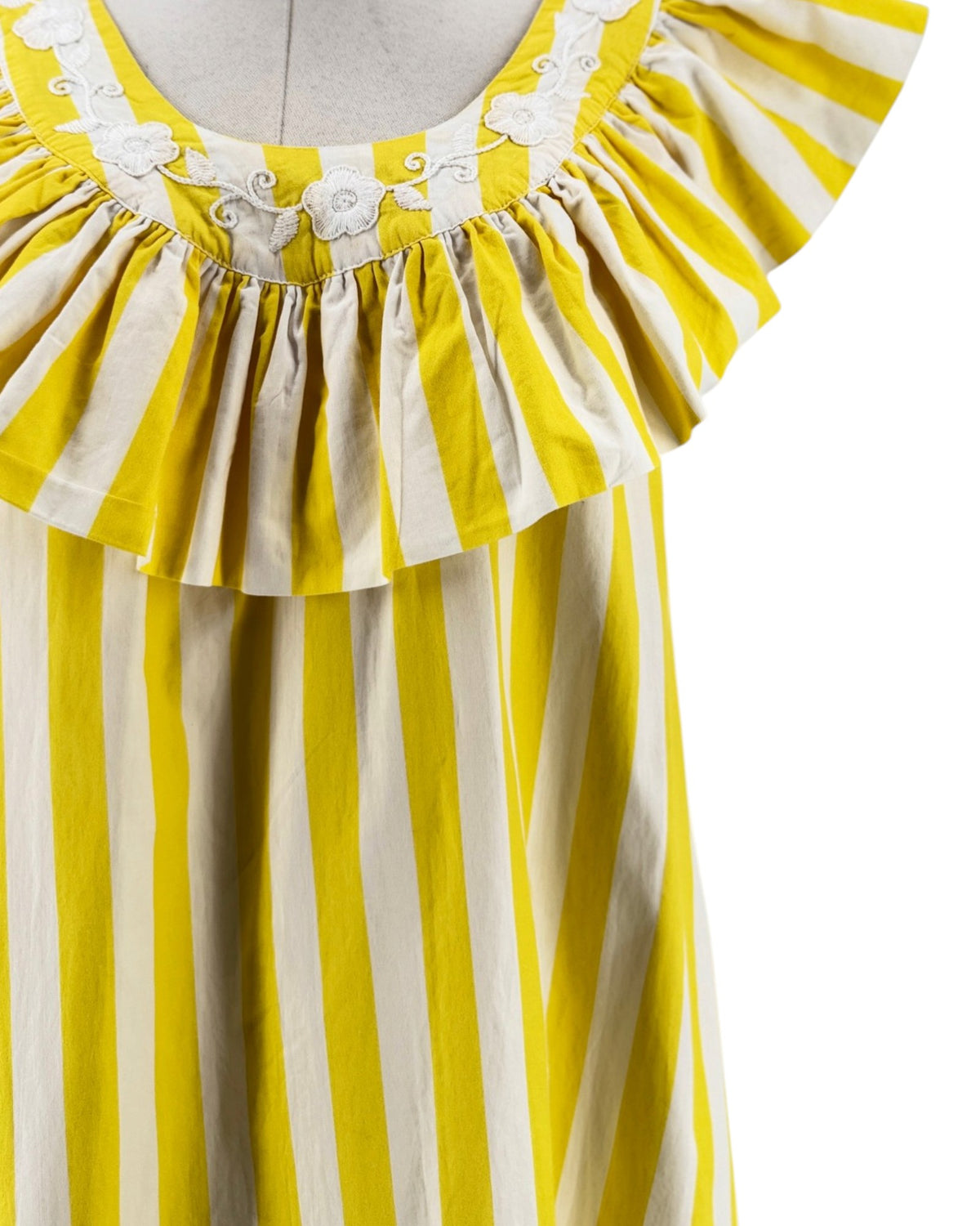 Yellow and white striped mini dress with white embroidered flowers along the neckline on a mannequin on a white background