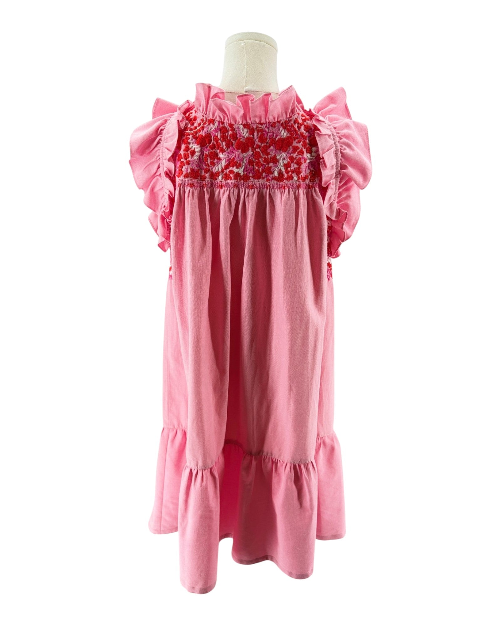 Pink dress with floral smocking on a mannequin against a white background