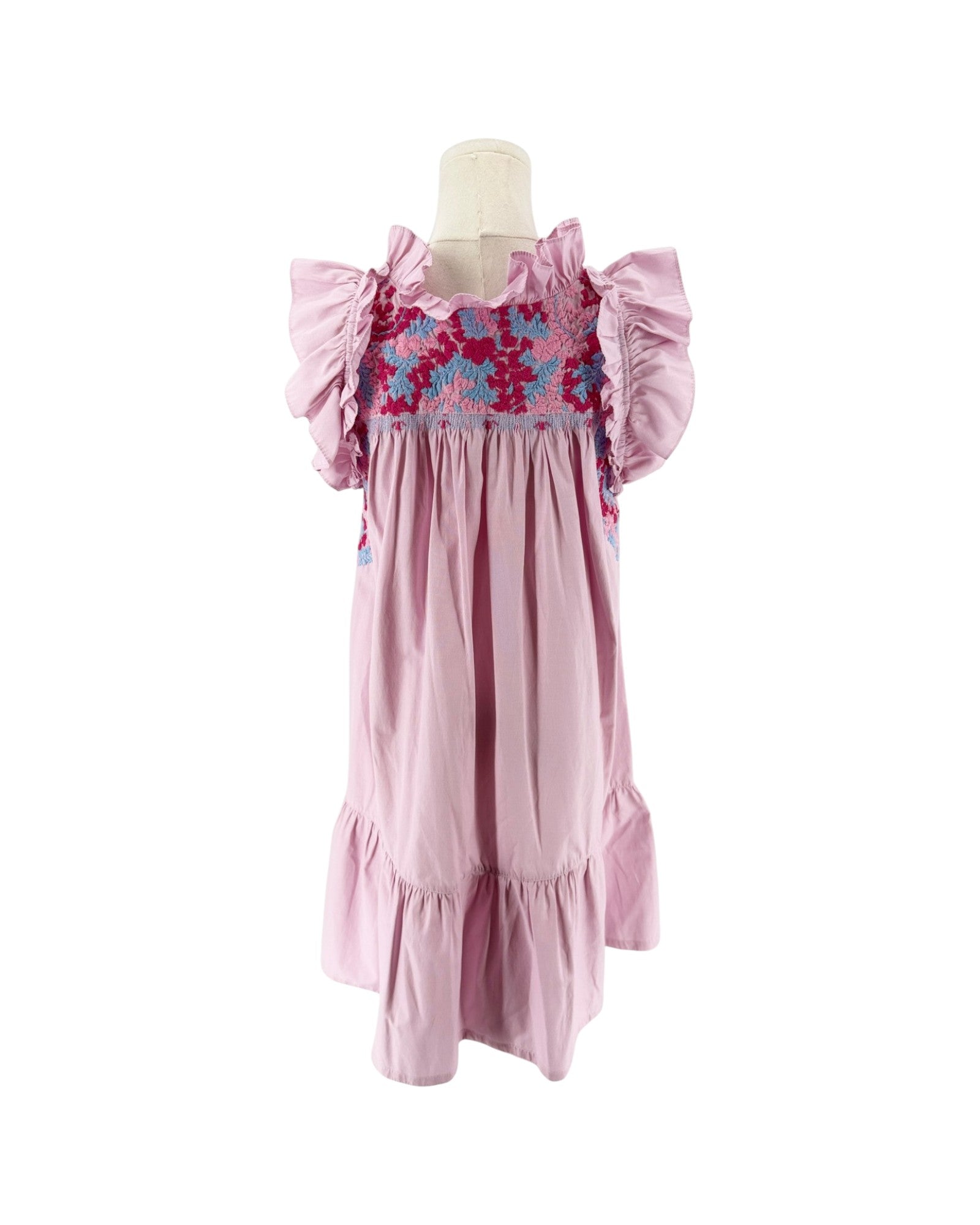 A pink smocked mini dress with ruffled sleeves and a colorful floral smocked bodice, displayed on a mannequin against a white background. 