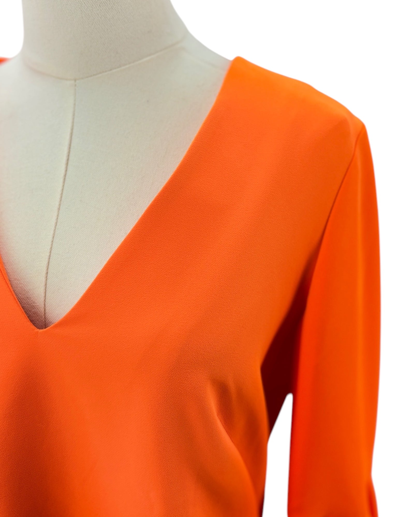 Orange long-sleeve top on a mannequin with a white background