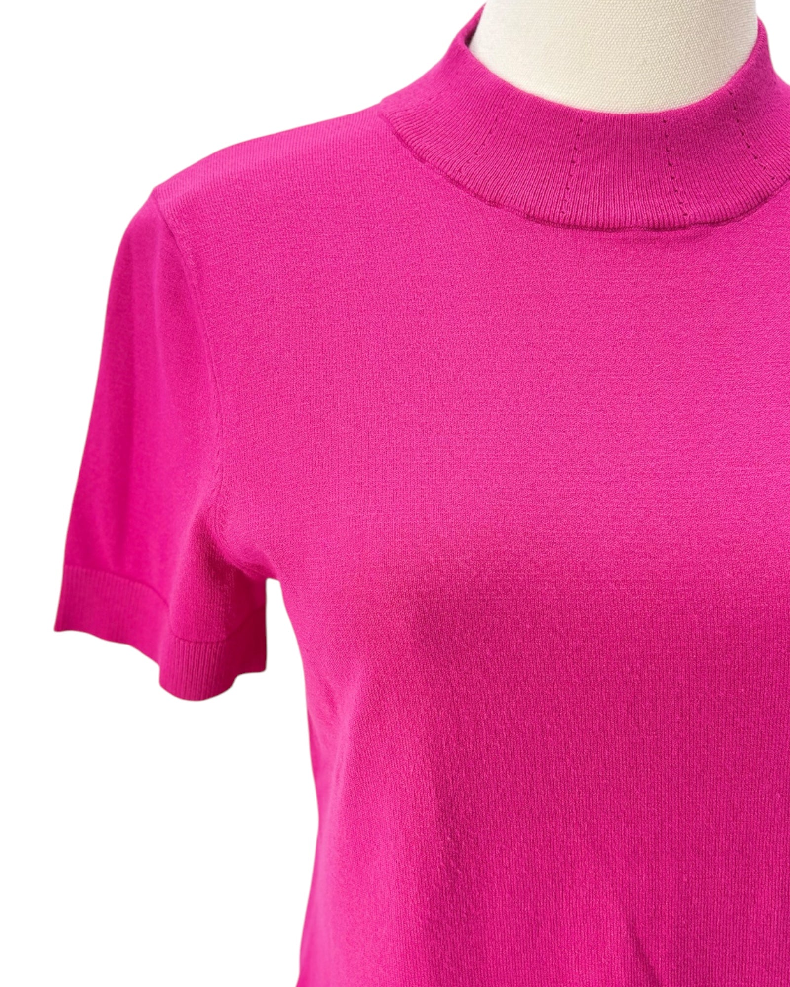 Pink short-sleeve knit shirt on a mannequin against a white background