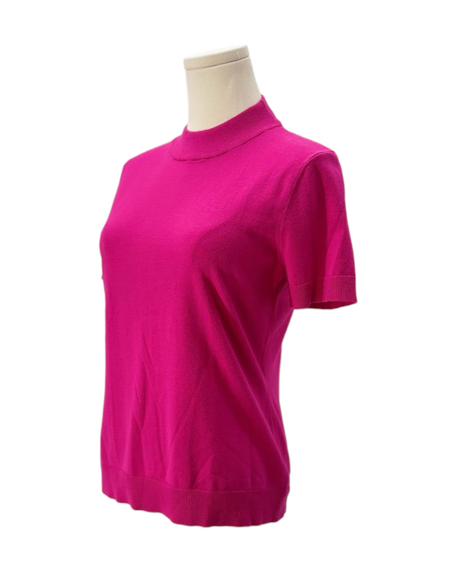 Pink knit shirt on a mannequin against a white background
