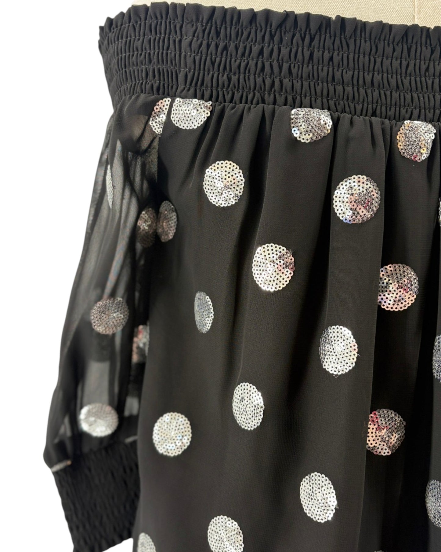 Milly black off-shoulder top with silver sequin polka dots on a mannequin against a white background