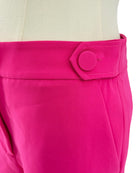 Close-up of bright pink shorts with a button on a white background