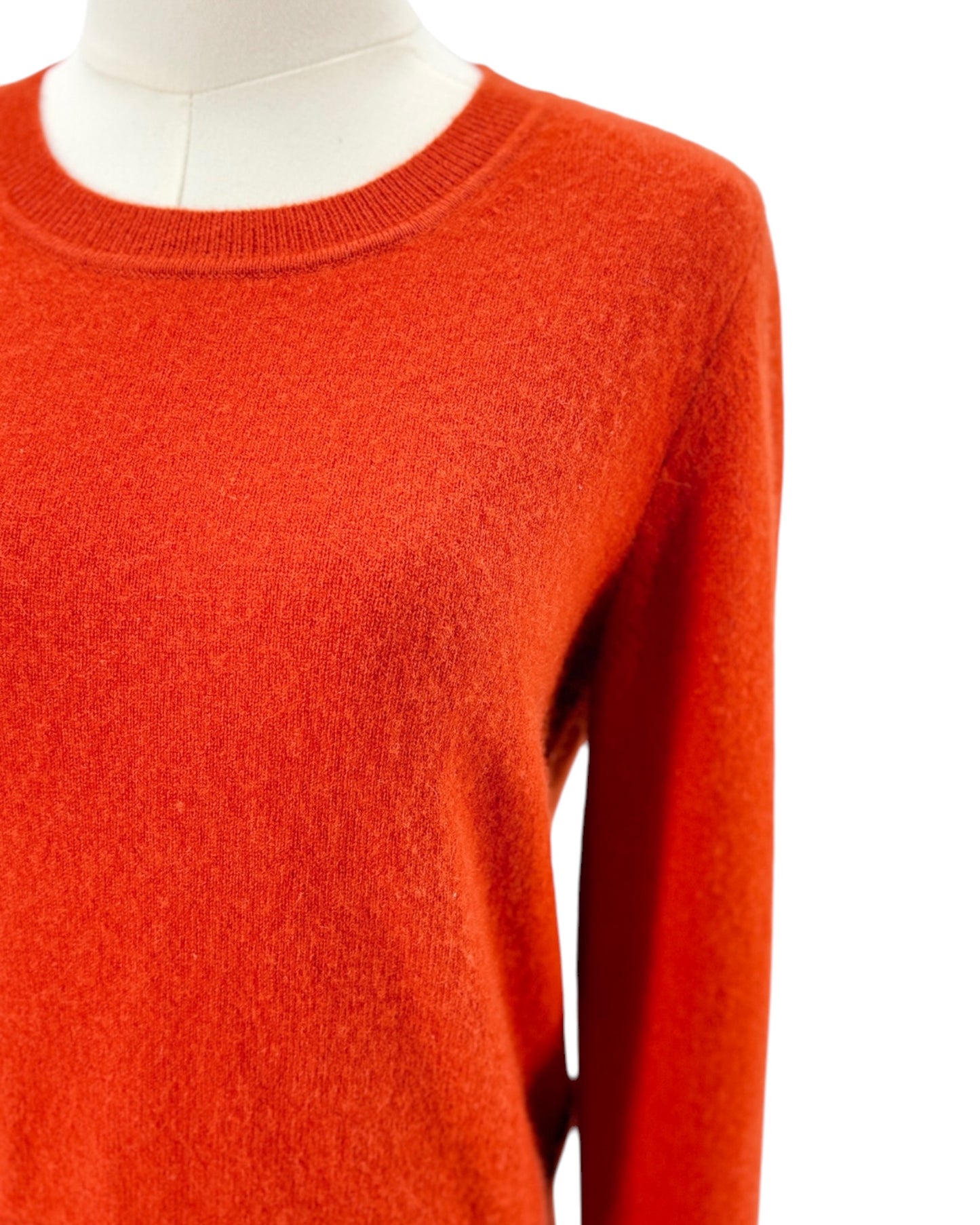 Orange red sweater on a mannequin against a white background