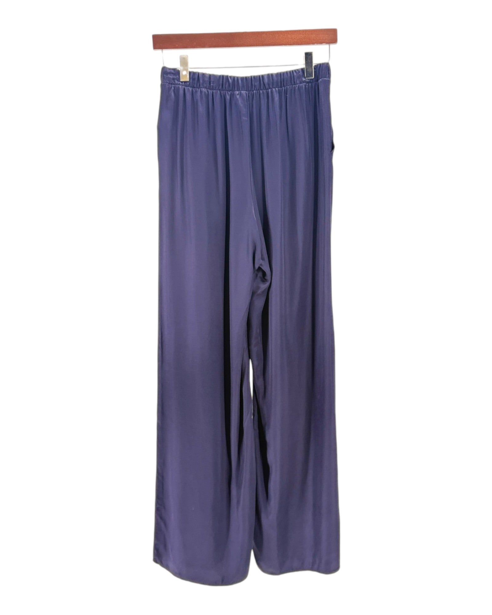 Pair of blue pants hanging on a wooden rod against a white background