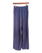 Pair of blue pants hanging on a wooden rod against a white background