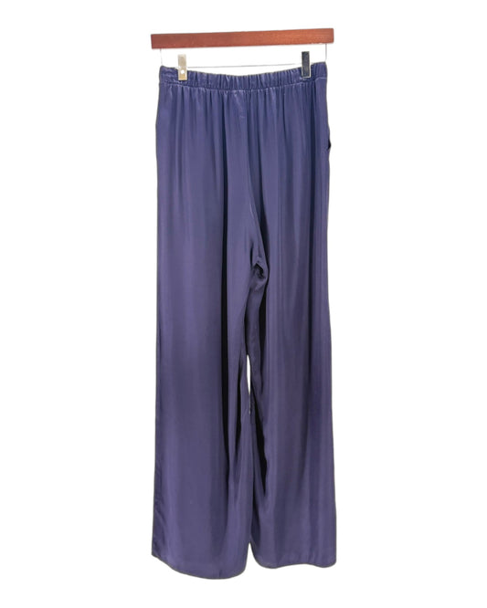 Pair of blue pants hanging on a wooden rod against a white background
