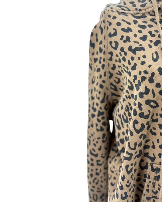 Close-up of a leopard print hoodie on a white background, showing the beige fabric with black spots and part of the hood.