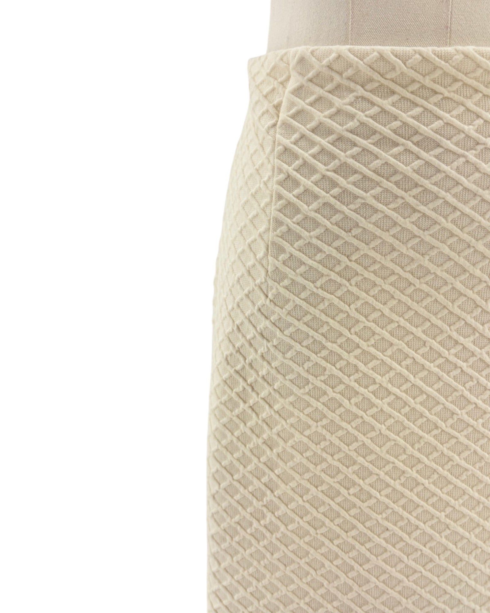 Close-up of a textured beige skirt on a mannequin against a white background