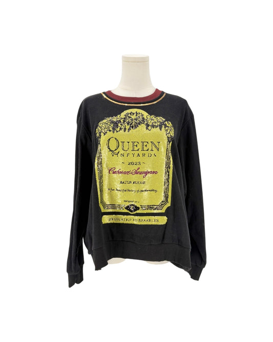 A black long-sleeve crewneck sweatshirt displayed on a mannequin torso against a white background. The sweatshirt features a large yellow vintage wine label graphic on the front with 'Queen Vineyards' text, and a small red inner collar.