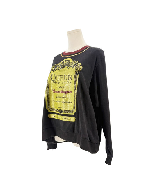 A black long-sleeve sweatshirt with a large yellow and gold Queen 'A Night at the Open Air' concert graphic on the front, displayed on a mannequin torso against a white background.