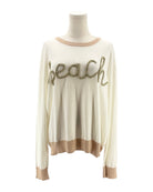 Beige sweater with 'beach' text on a mannequin against a white background
