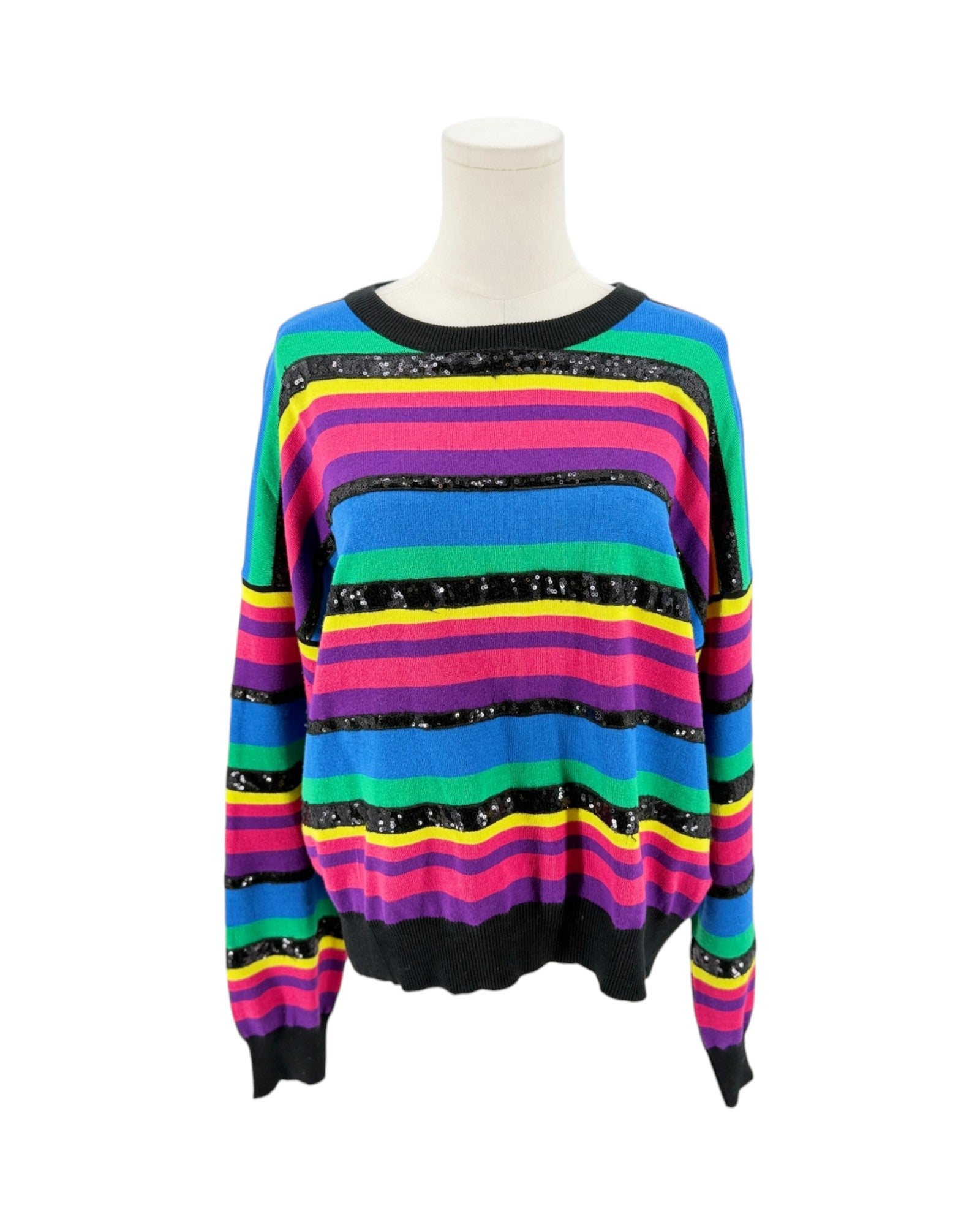 A long-sleeve knit sweater with horizontal rainbow stripes in pink, blue, green, yellow, and orange, accented with black sequined bands, displayed on a white mannequin torso against a white background.