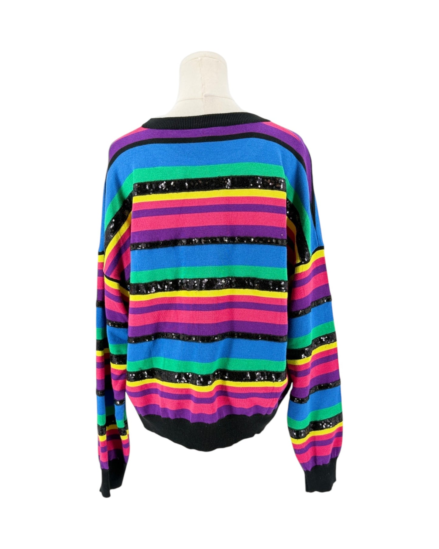 A long-sleeve knit sweater with horizontal rainbow stripes in blue, green, yellow, pink, purple, and black, displayed on a mannequin torso against a white background.