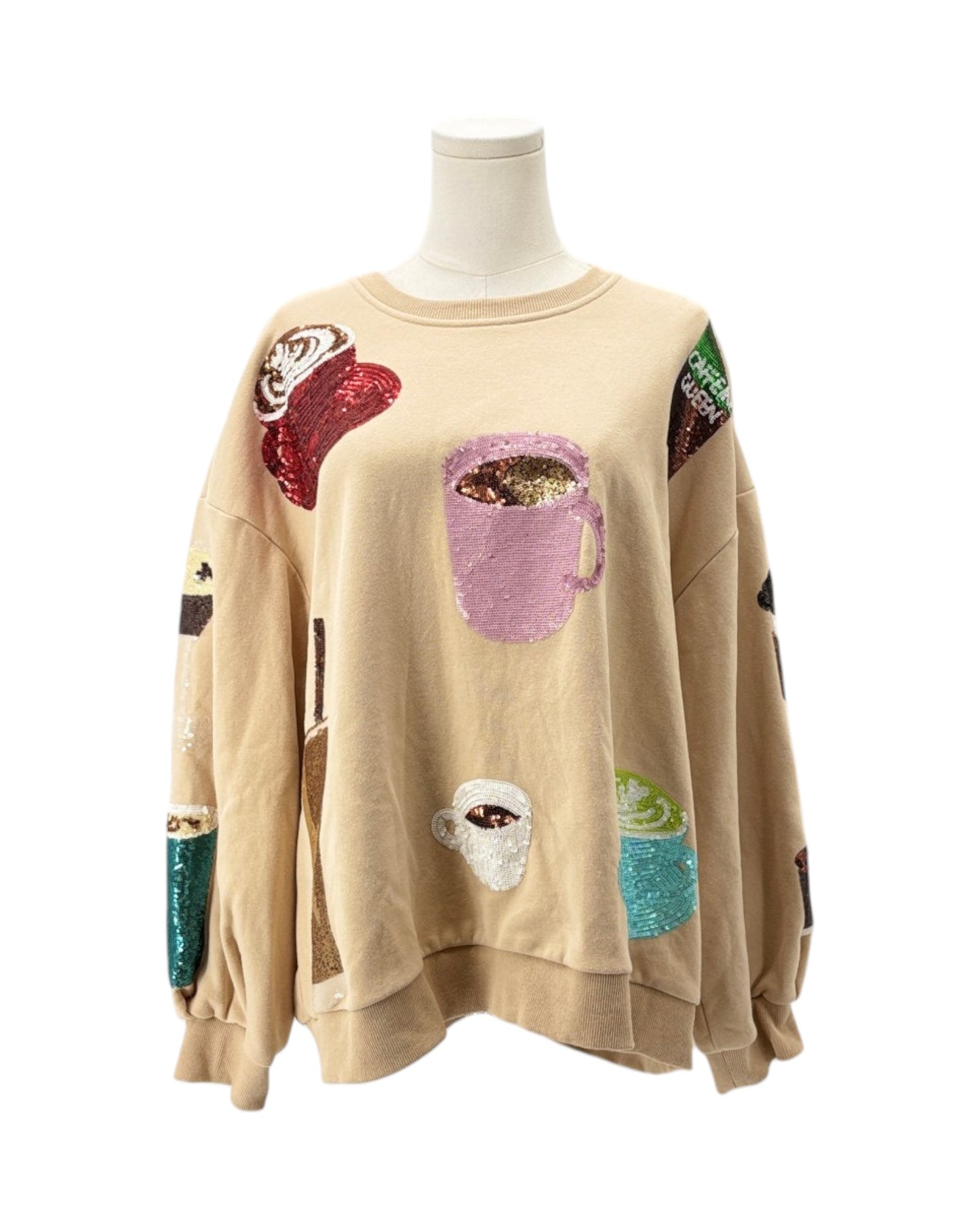 Beige sweater with colorful coffee-themed patches on a mannequin against a white background