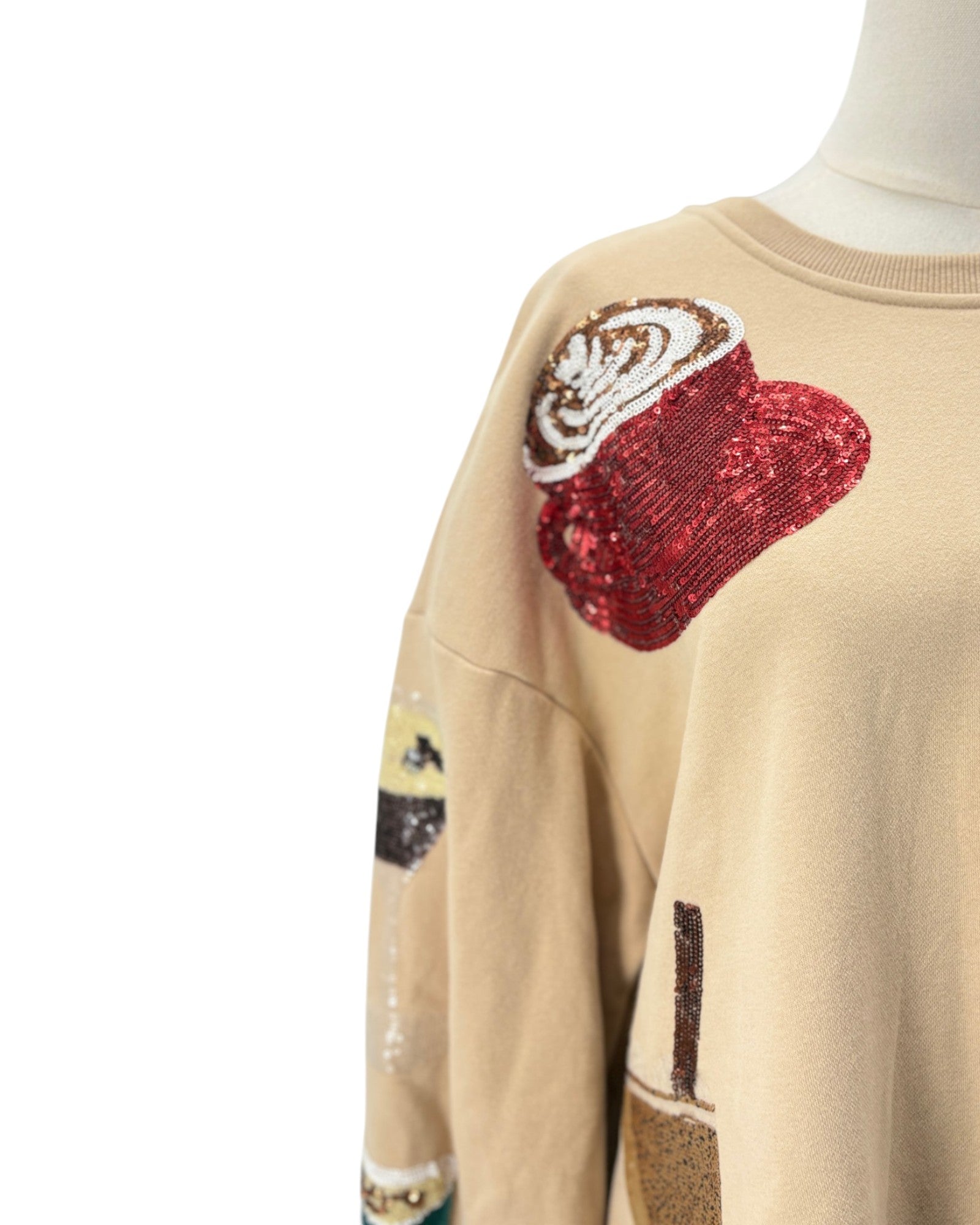 Beige sweatshirt with decorative patches on a white background