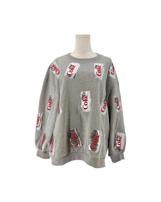 A gray crewneck sweatshirt displayed on a mannequin torso, featuring an all-over print of silver Coca-Cola cans with red script logos.
