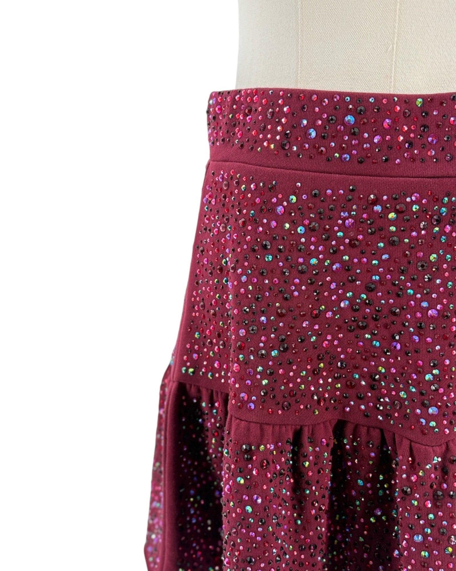 Maroon skirt with colorful embellishments on a mannequin against a white background