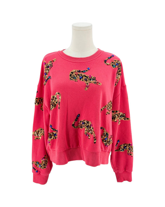 A bright pink crewneck sweatshirt displayed on a white mannequin torso. The sweatshirt features an allover pattern of stylized crocodile silhouettes filled with a leopard print design in black, beige, and brown, accented with small blue and yellow details.