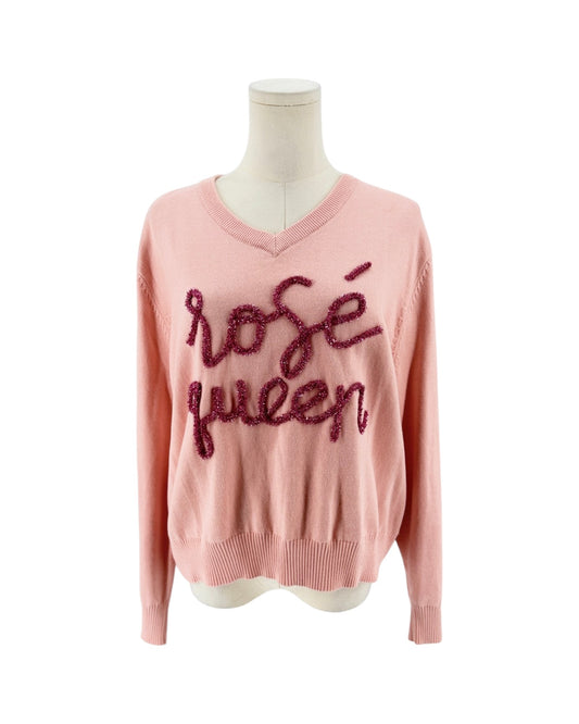 A light pink knit sweater with a V-neck and long sleeves, featuring the words 'rosé queen' written across the chest in dark pink sequined script, displayed on a mannequin torso against a white background.