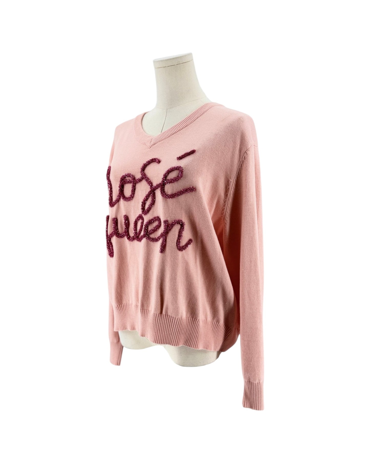 A light pink knit sweater with 'rose queen' written across the chest in dark pink sequins, displayed on a cream mannequin torso against a white background.
