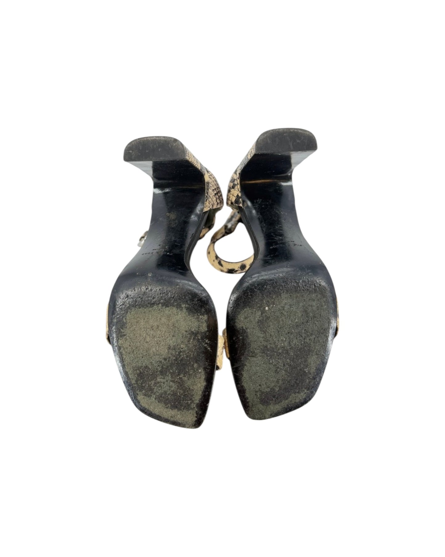A pair of vintage black high-heeled shoes shown from the sole view, featuring a textured black leather upper and a gold-tone chain detail connecting them, set against a plain white background.