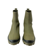 Pair of green rubber boots with black soles on a white background
