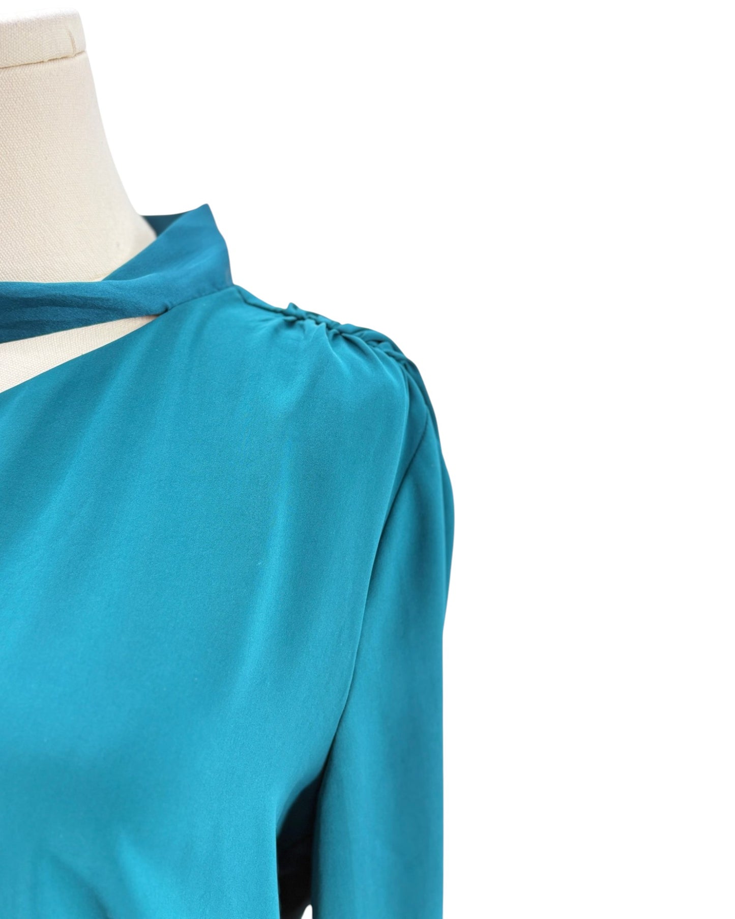 Teal blouse on a mannequin with a white background