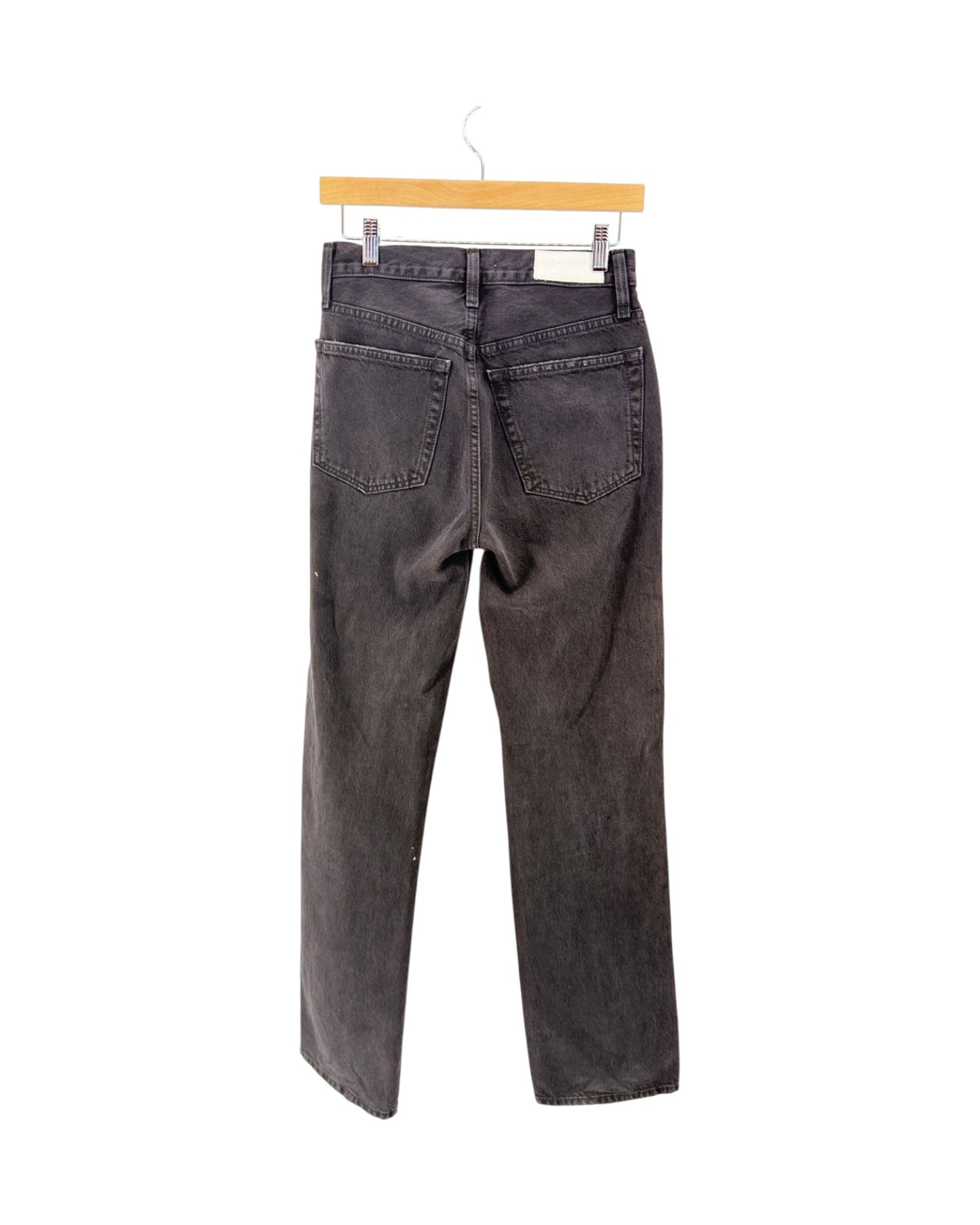 A pair of dark gray washed denim jeans shown from the back, hanging from a light wood hanger against a plain white background.